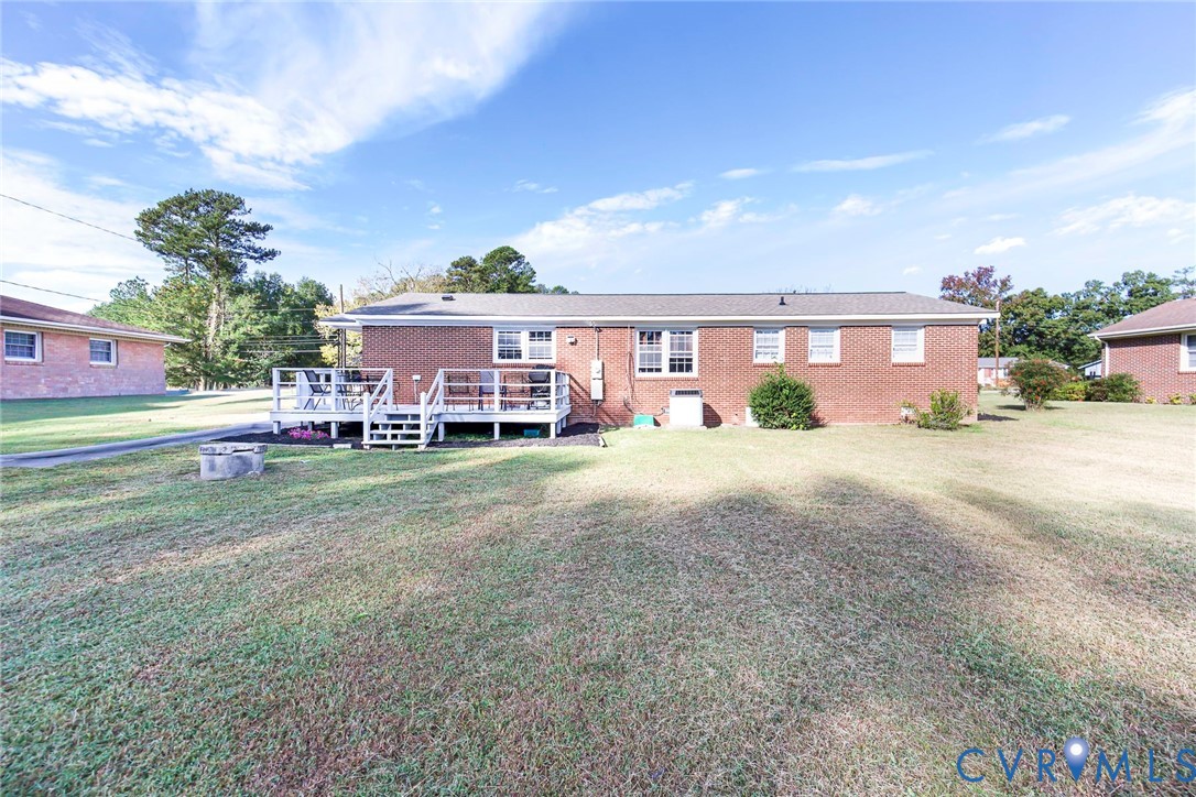 Brick exterior residence featuring a raised wood deck, multi-pane windows, and an expansive lawn