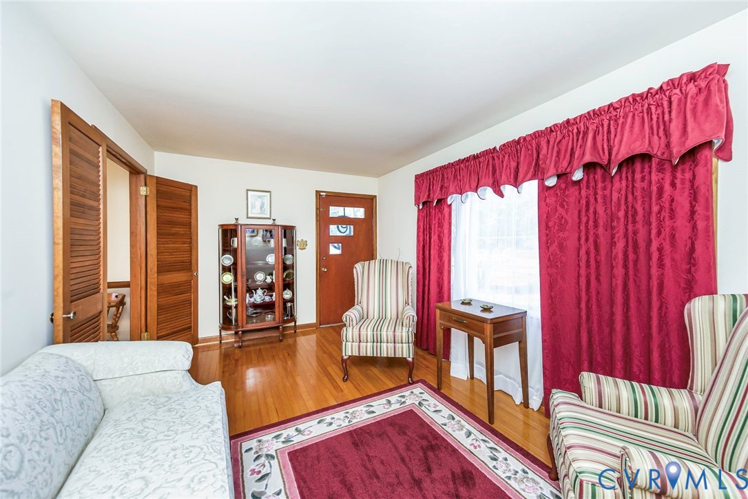 Hardwood flooring, wood-panel door with decorative glass inserts, and louvered wood interior doors