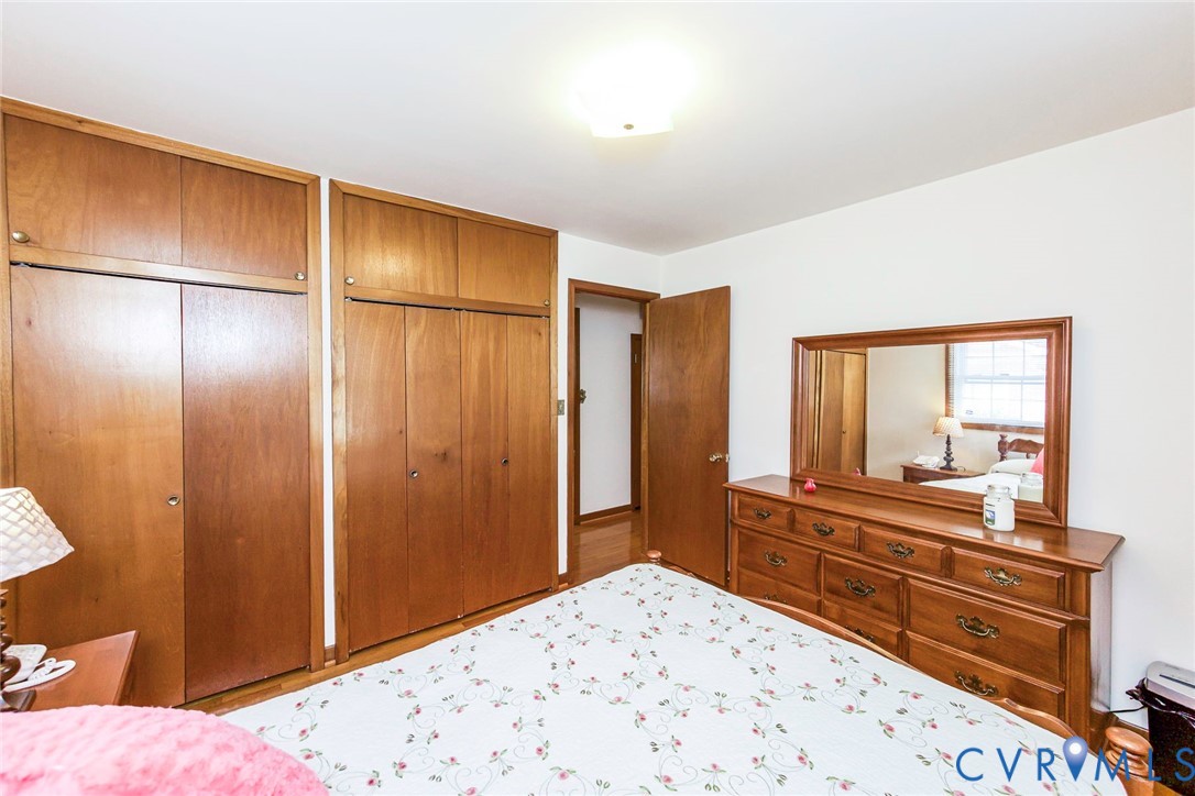 Floor-to-ceiling wooden built-in cabinetry with overhead storage, wood-finish flooring, and a flush-mount ceiling light fixture