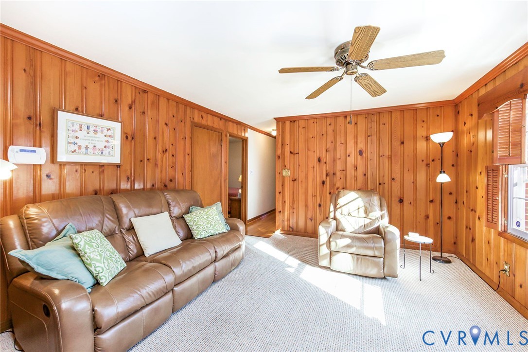 Interior featuring wood paneling, wall-to-wall carpeting, and a ceiling-mounted paddle fan