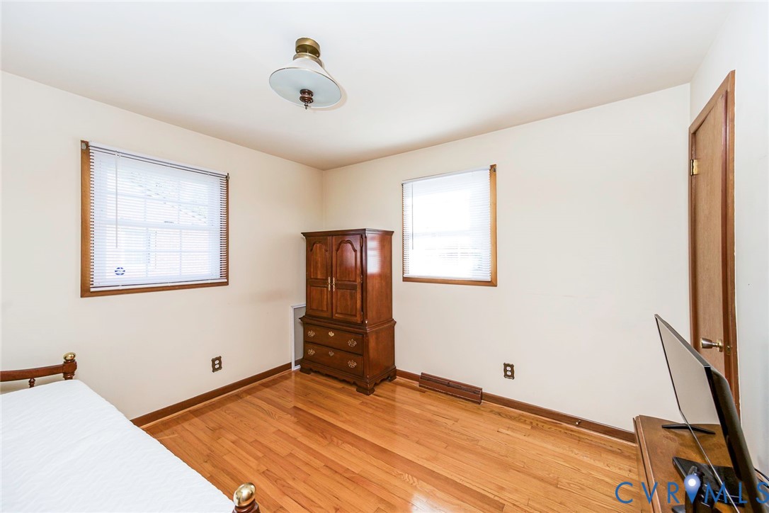 Room featuring wood-finish flooring, two windows with wood-framed trim, and a centered flush-mount light fixture