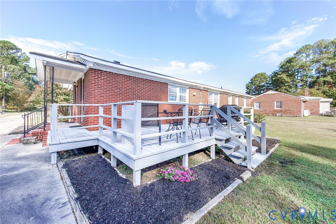 Red brick exterior featuring a raised wood-deck platform, metal railings, and a concrete walkway