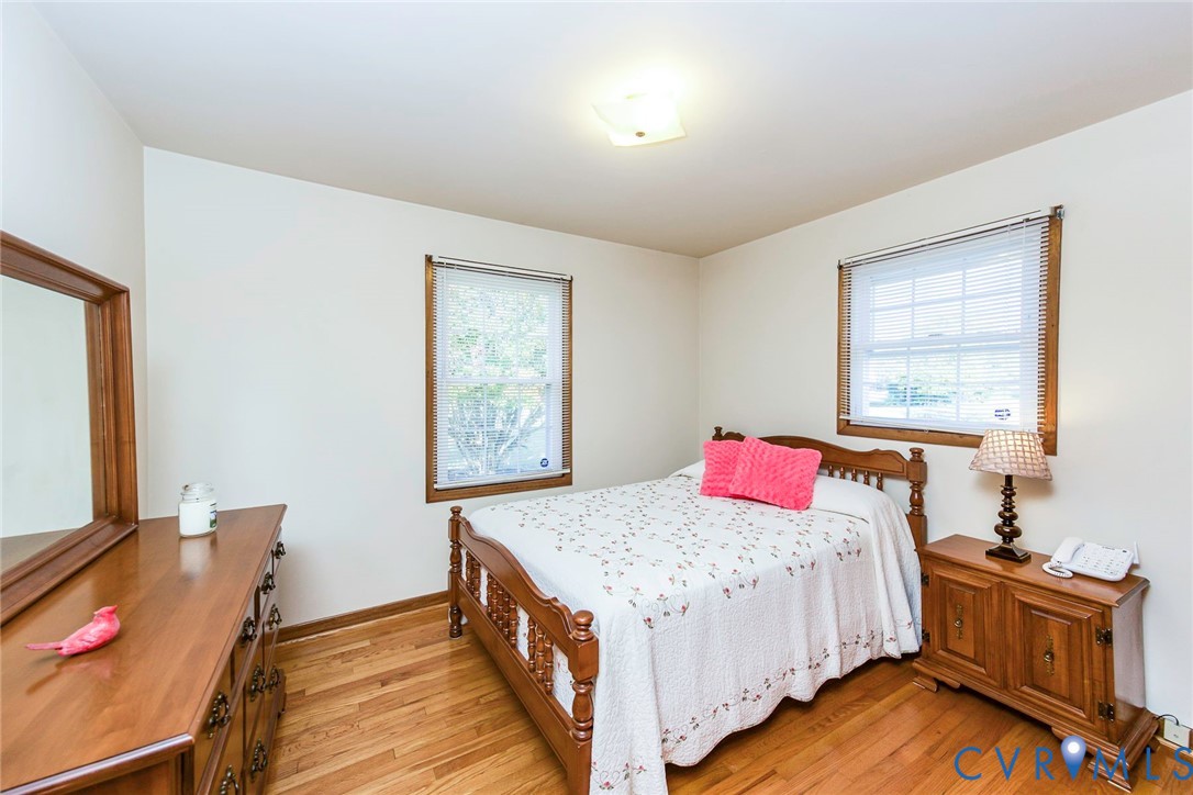 Room featuring wood-finish flooring, two windows with wood-trimmed frames, and a flush-mount ceiling light fixture