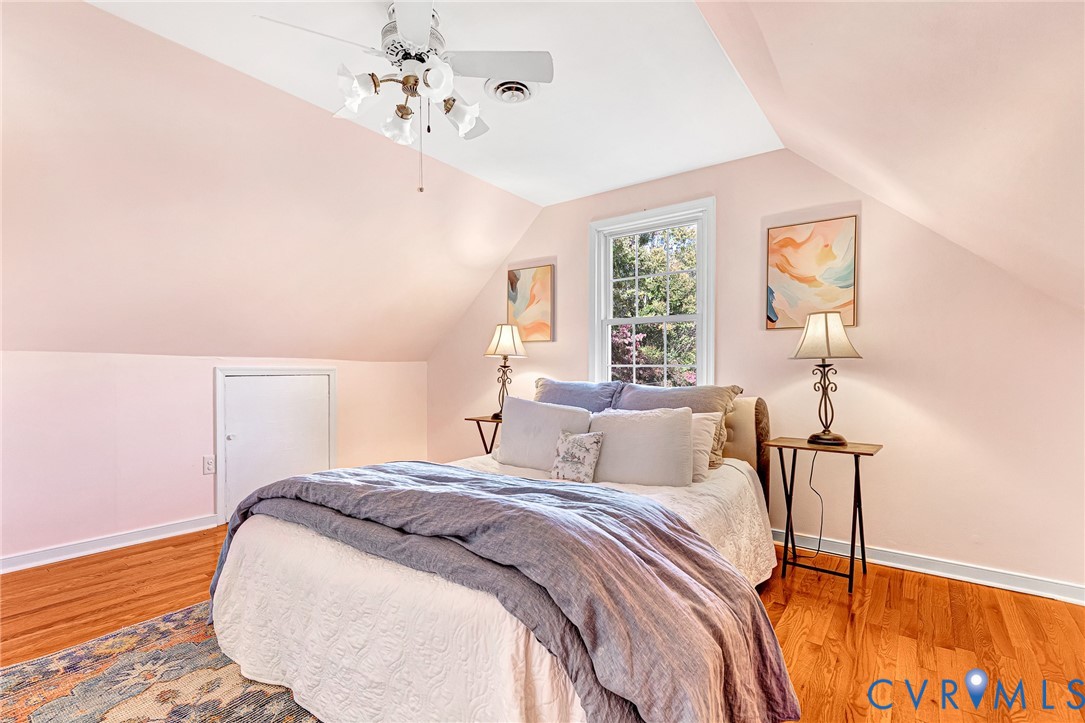 Vaulted ceilings with an integrated multi-light ceiling fan, polished wood-finish flooring, and built-in attic access panel