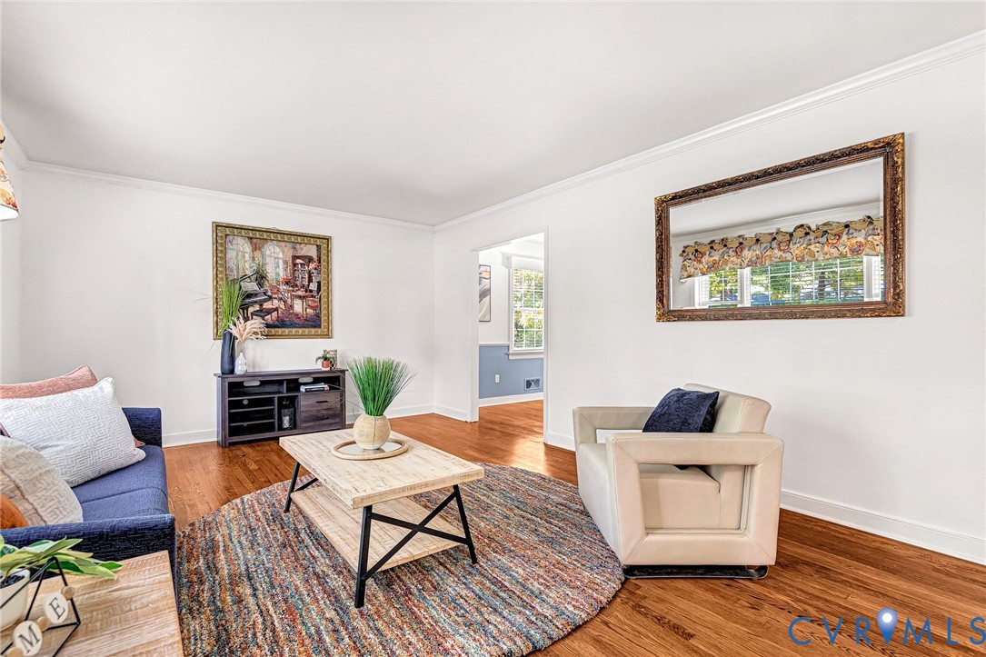 Living area featuring wood-finish flooring, crisp crown molding, and neutral wall tones