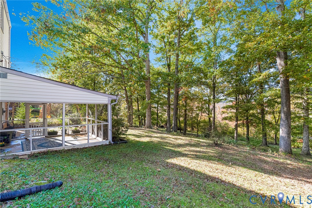 Screened-in porch featuring white structural framing, wood-finish flooring, and expansive natural surroundings with mature trees