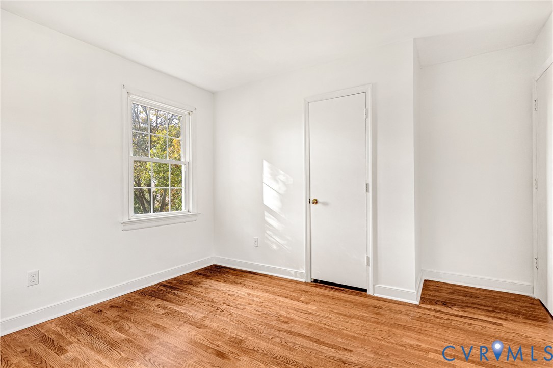 Room featuring wood-finish flooring, white walls, and a multi-pane window