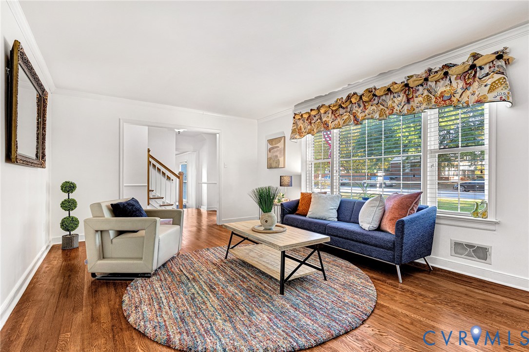 Hardwood flooring, crown molding, and large picture windows featuring white slatted blinds