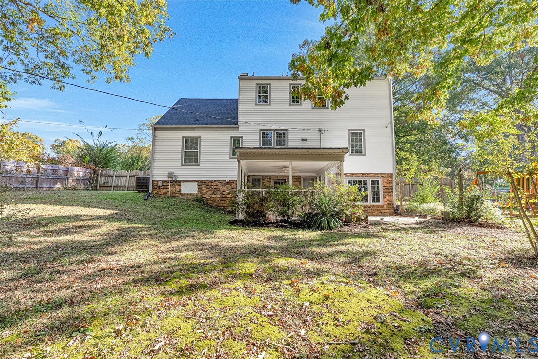 Multi-level exterior featuring white horizontal siding, a stone veneer foundation, a covered rear porch, and a fenced yard