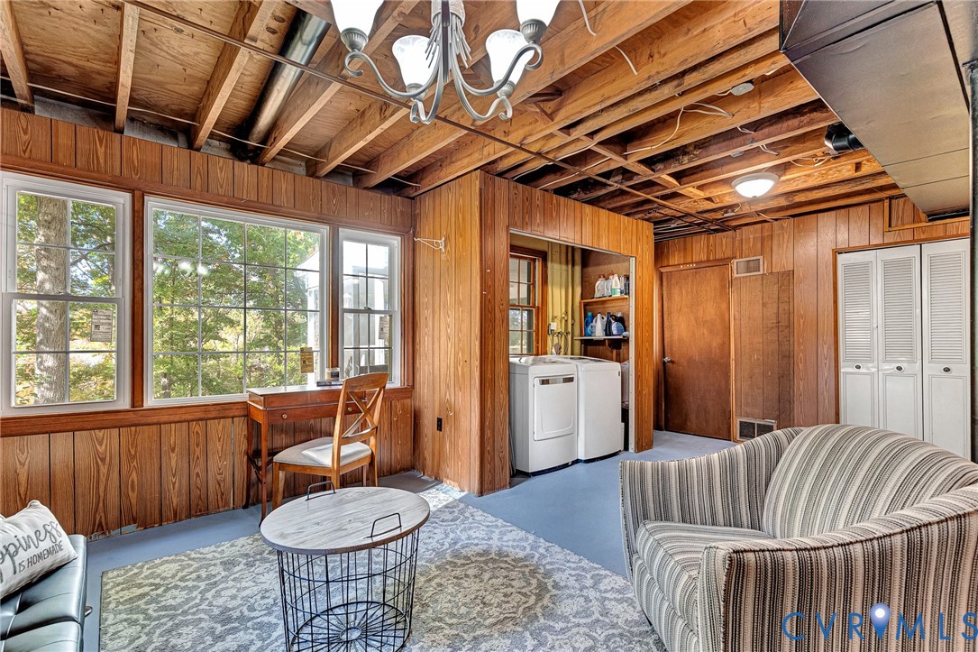Wood-paneled walls, exposed timber ceiling joists, multi-pane windows, and dedicated laundry alcove