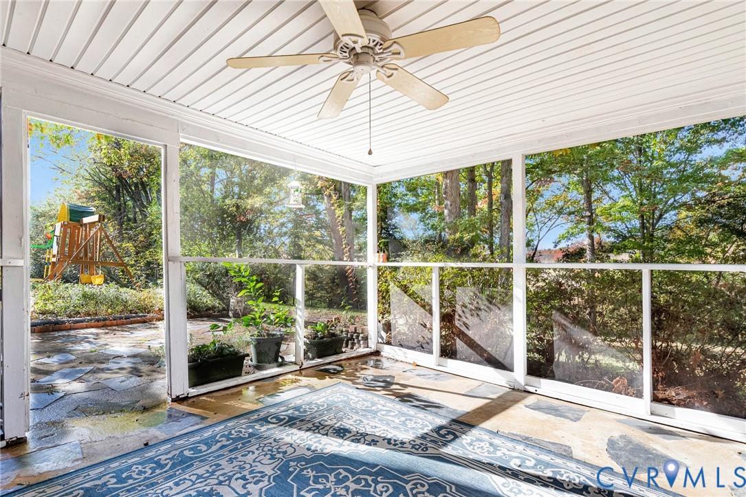 Screened-in porch featuring a beadboard ceiling, overhead paddle fan, and flagstone flooring
