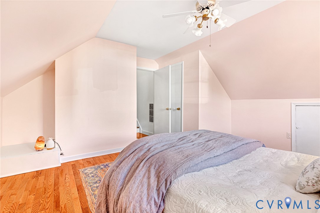 Vaulted ceiling with a central multi-light ceiling fan and built-in eaves storage, featuring hardwood flooring