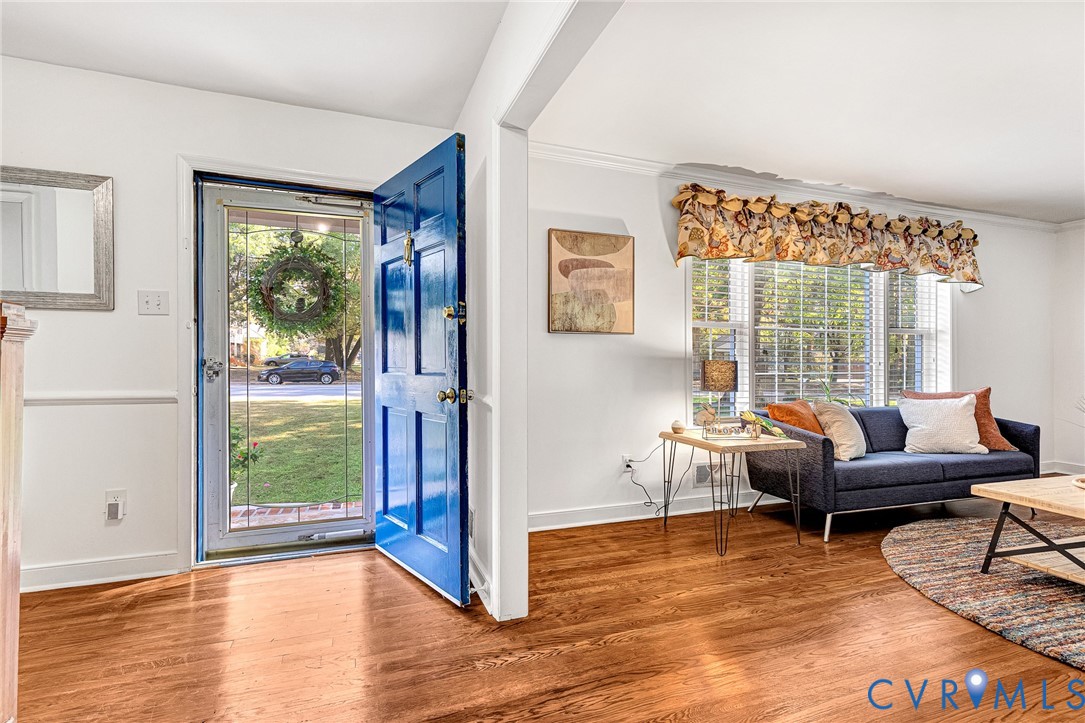 Entryway featuring wood-finish flooring, a six-panel exterior door, and wainscoting, including a window with crown molding