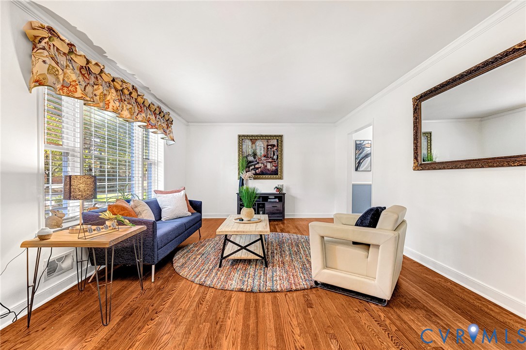 Living area featuring wood-finish flooring, multi-pane windows, and crown molding