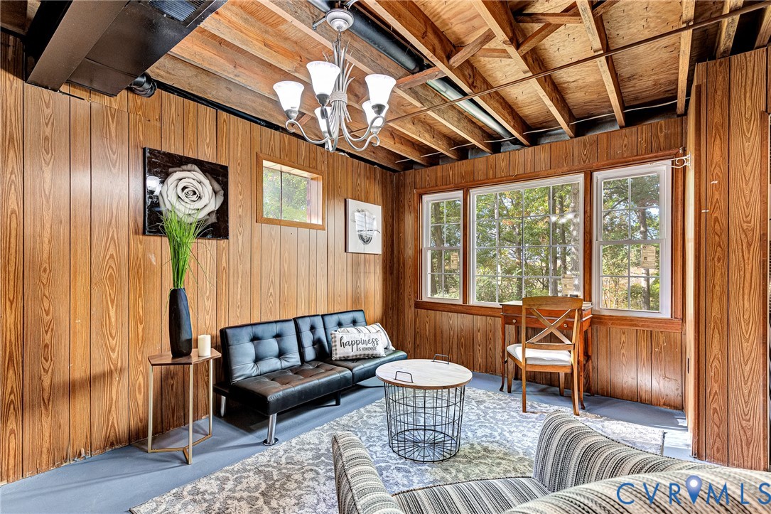 Wood-paneled walls, exposed ceiling joists, multi-light chandelier, and triple-pane window configuration