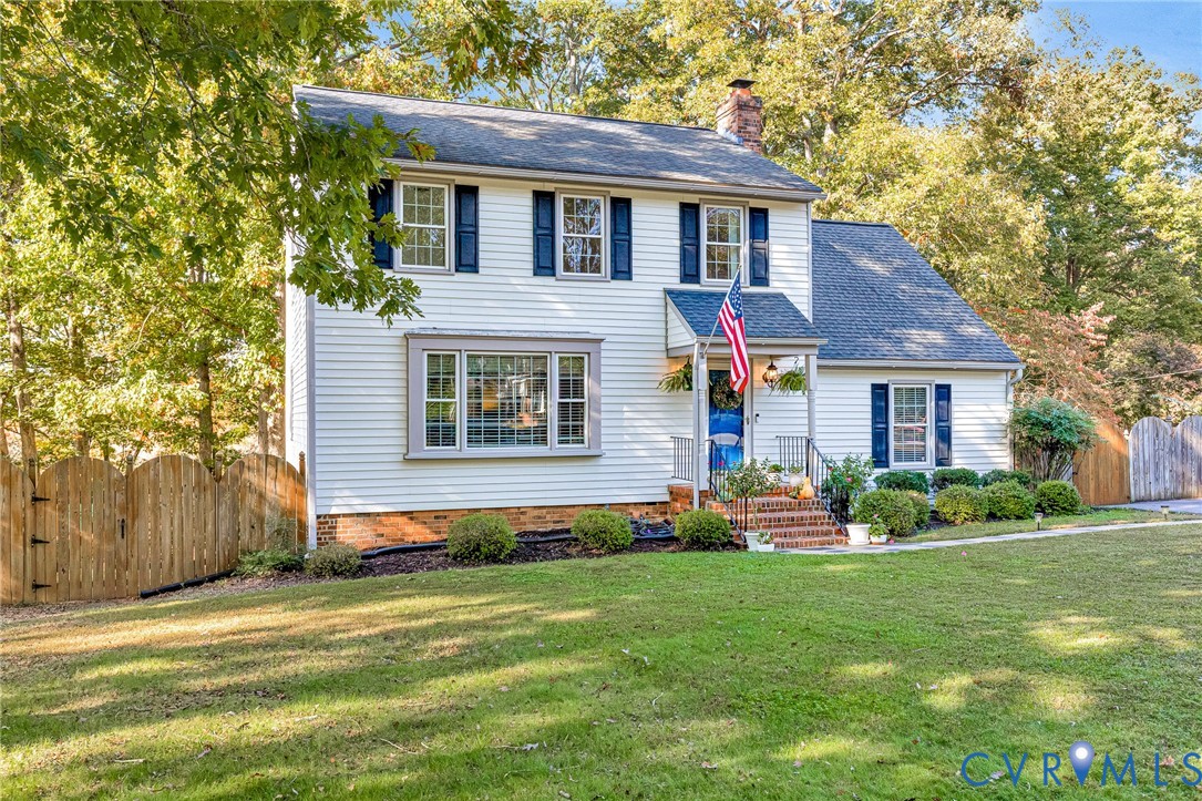 Two-story exterior featuring light-colored horizontal siding, dark shutters, a front entry with a covered porch, brick steps, and a multi-pane bay window Two-story exterior featuring light-colored horizontal siding, dark shutters, a front entry with a covered porch, brick steps, and a multi-pane bay window