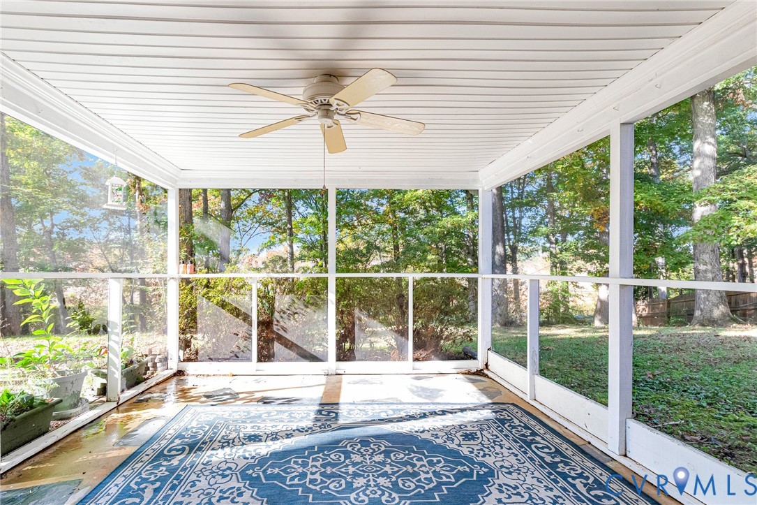 Screened porch featuring white-painted structural framing, beadboard ceiling, and a ceiling fan