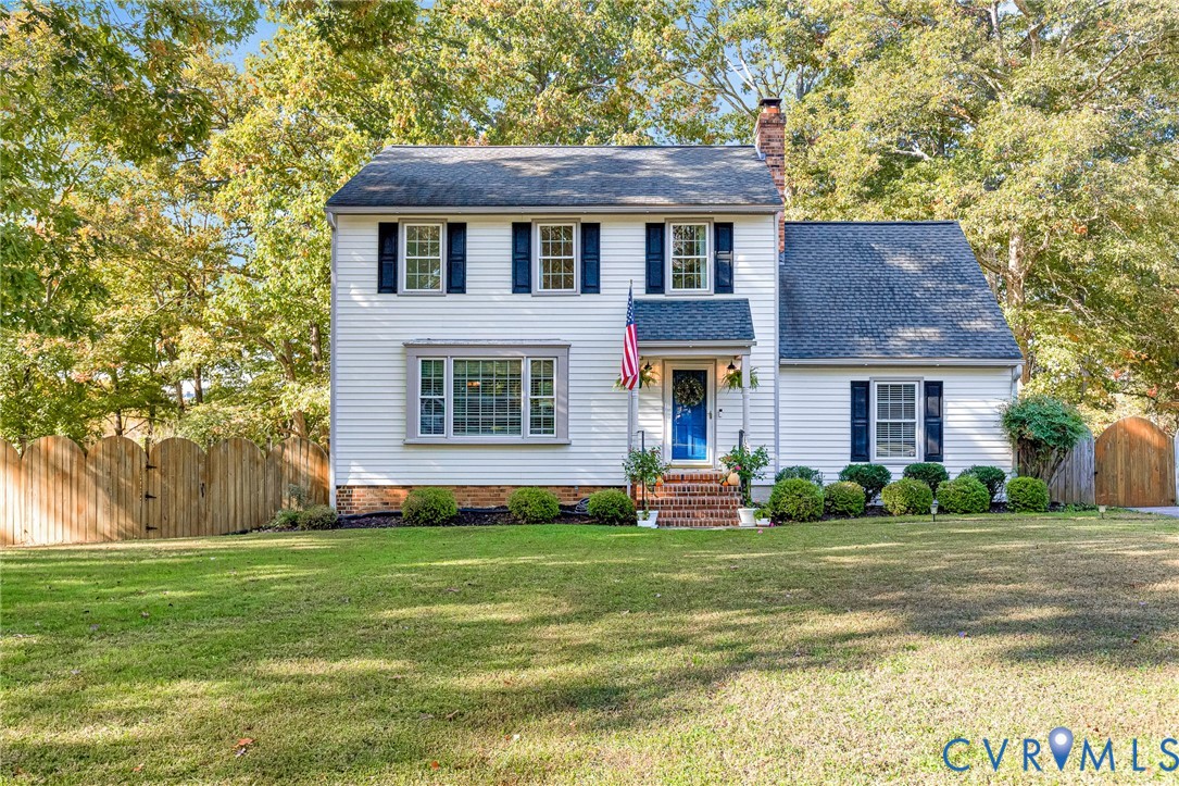 Two-story Colonial exterior featuring light siding, dark shutter accents, a brick front stoop, and a wood-slat privacy fence