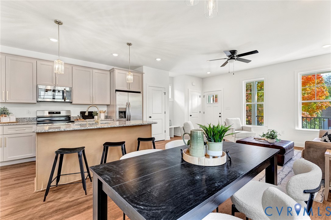 Kitchen featuring flat-panel cabinetry, stone countertops, a central island, stainless steel appliances, and wood-finish flooring