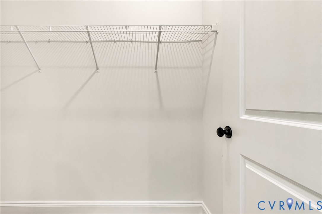 Storage area featuring white paneled door with matte black hardware and white wire shelving