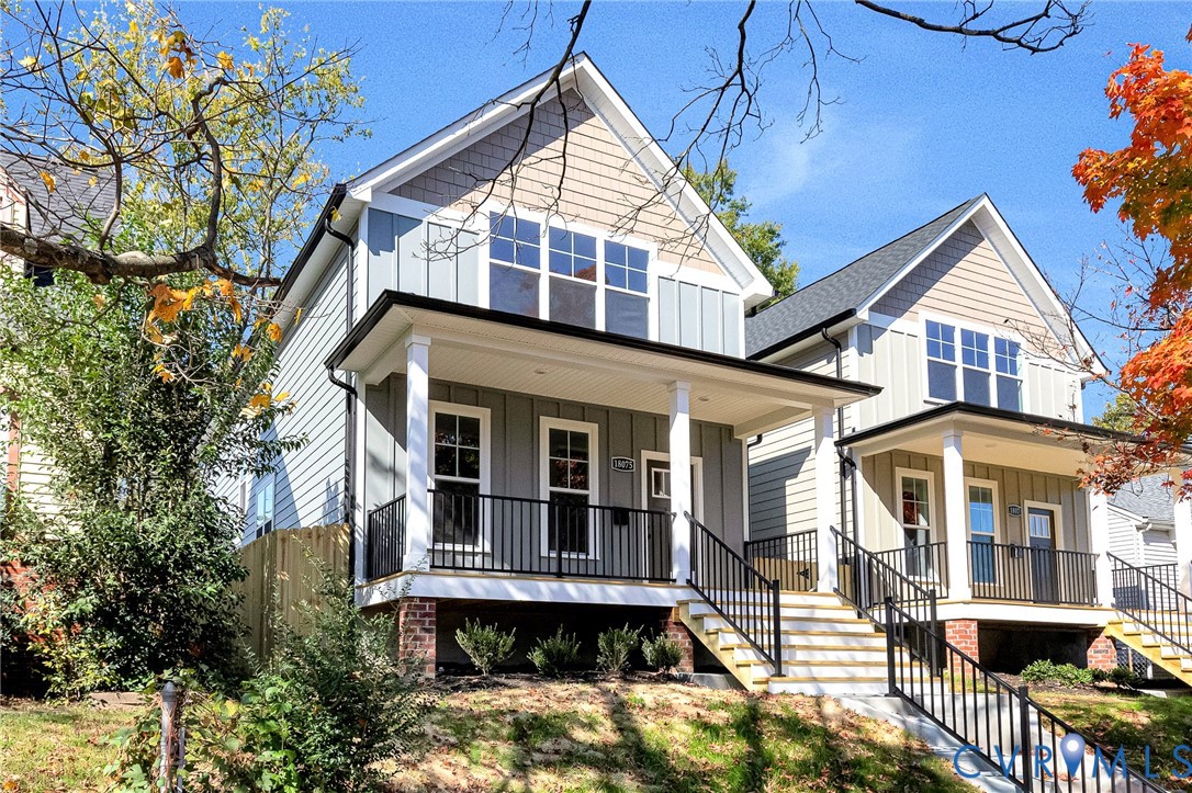 Gabled exterior featuring board-and-batten siding, a covered front porch, brick foundation detailing, and black metal railings Gabled exterior featuring board-and-batten siding, a covered front porch, brick foundation detailing, and black metal railings