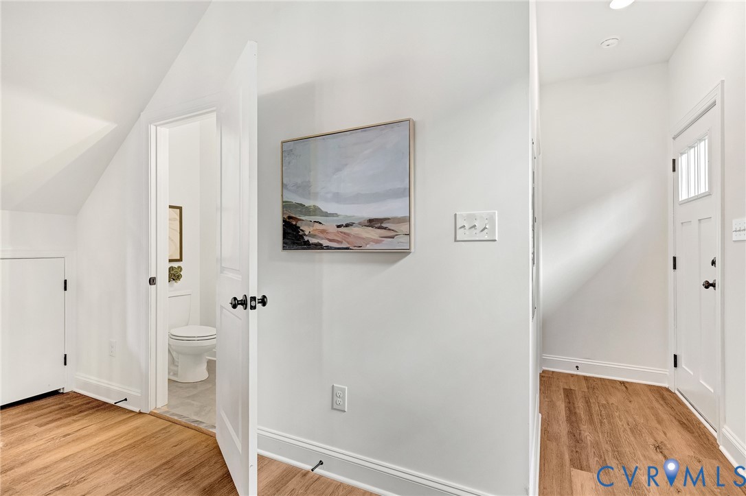 Wood-finish flooring, vaulted ceilings, and white interior doors featuring matte black hardware