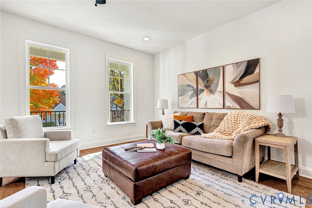 Living room featuring tall windows with divided lites, recessed lighting, and wood-finish flooring