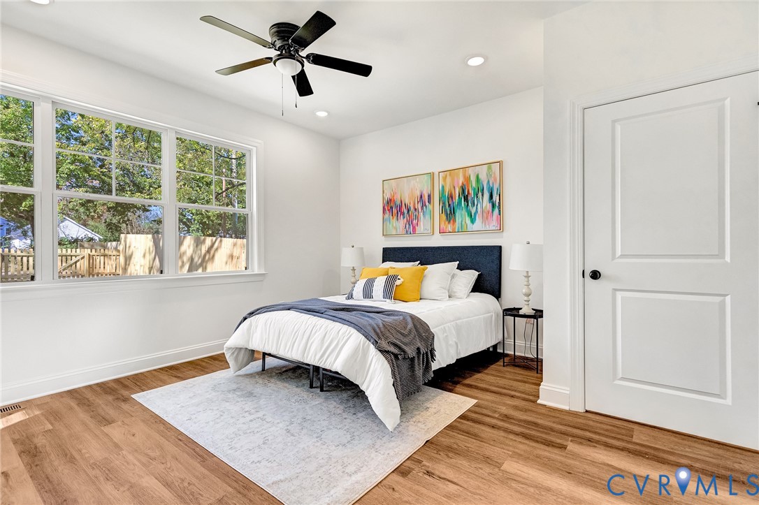 Room featuring wood-finish flooring, recessed lighting, a multi-pane window, and a ceiling fan