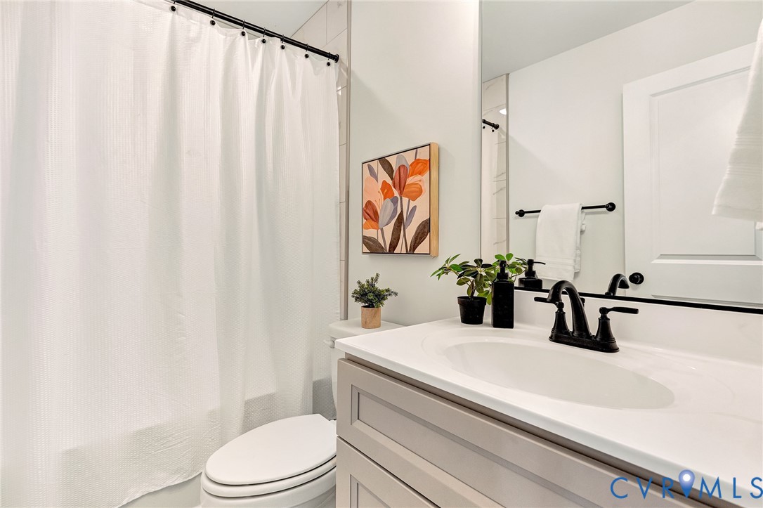 Bathroom featuring a vanity with shaker-style cabinetry, an integrated sink, matte black plumbing fixtures, a full-width mirror, and a tub-shower combination with floor-to-ceiling tile surround