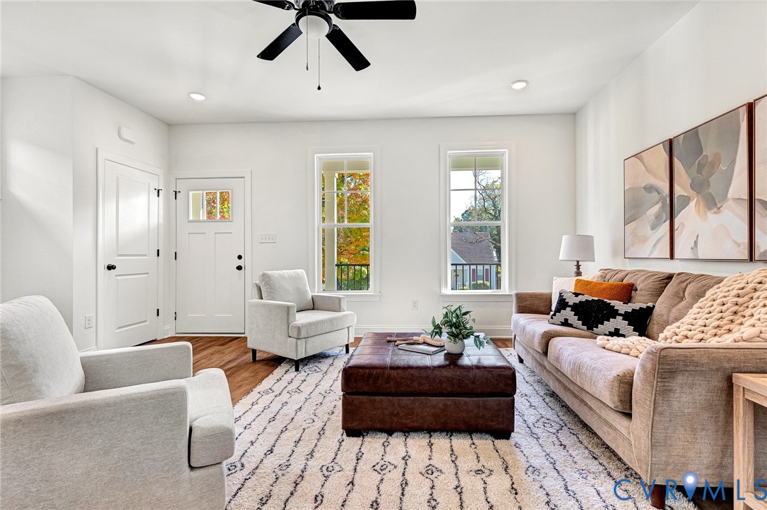 Wood-finish flooring, tall windows with muntin detailing, recessed lighting, and a central ceiling fan