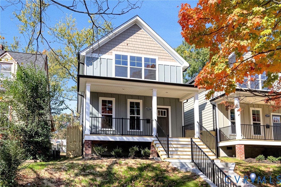 Two-story exterior featuring vertical board-and-batten siding, shake-shingle gables, a covered front porch with metal railings, and a brick-accented foundation