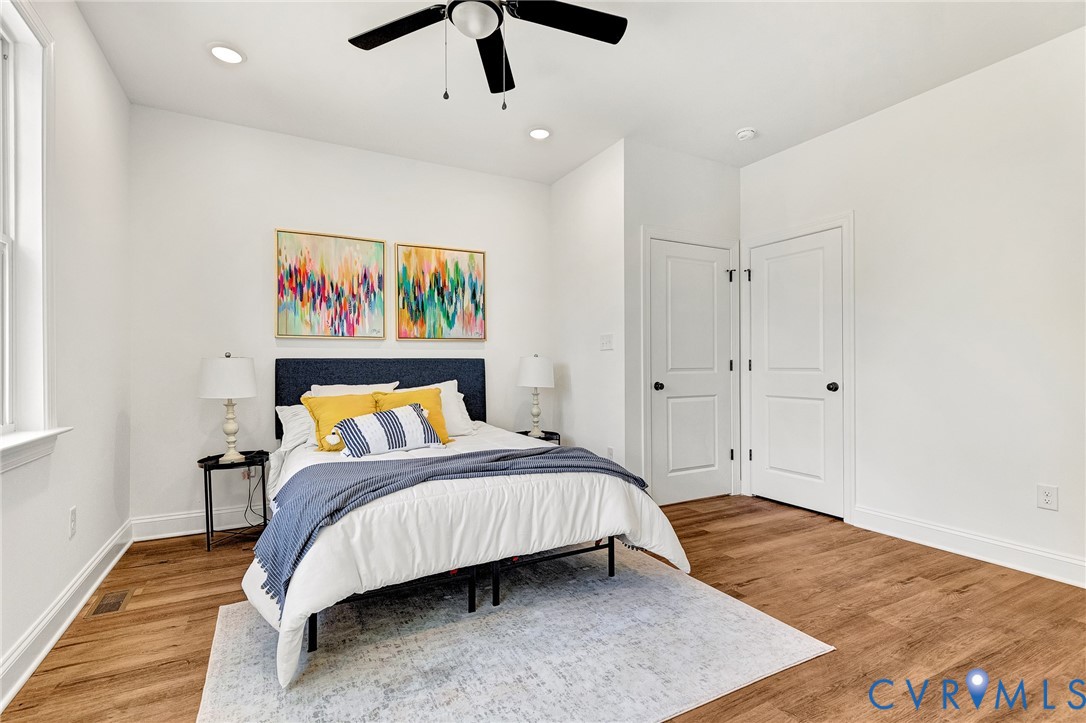 Room featuring wood-finish flooring, recessed lighting, a ceiling fan with integrated lighting, and two multi-panel interior doors