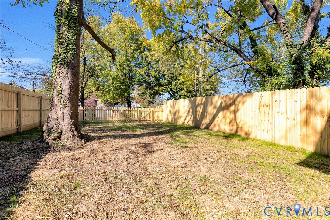 Backyard featuring a wood-panel fence, gated entry, and mature trees