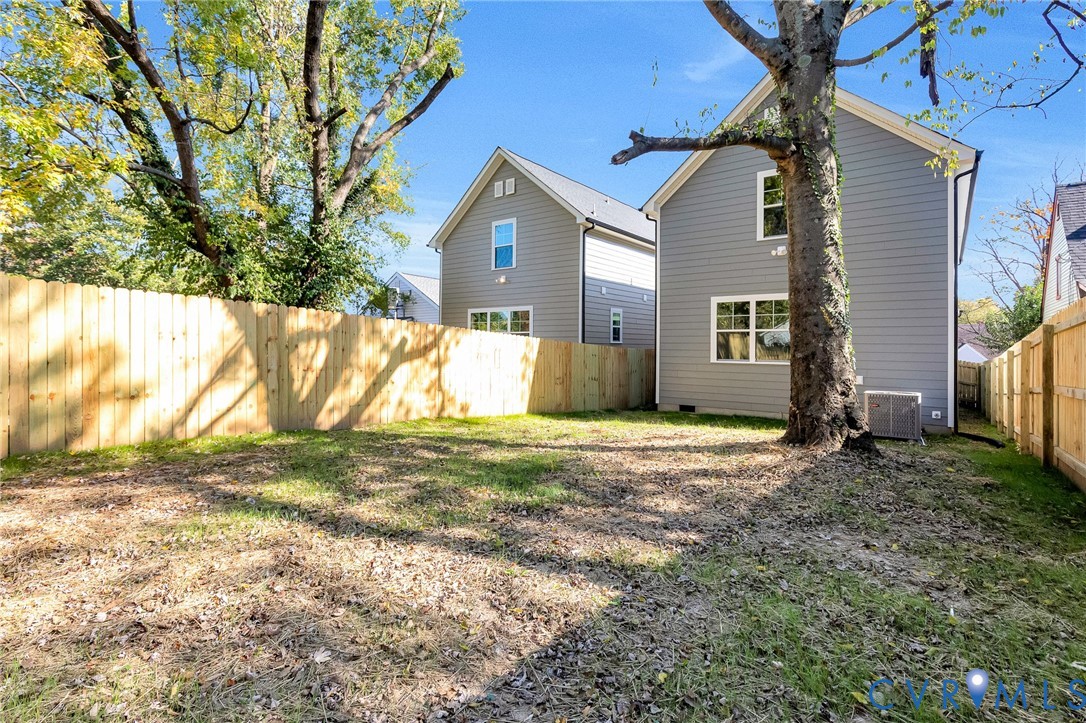 Rear yard featuring horizontal wood privacy fencing, mature trees, and grey lap siding exterior
