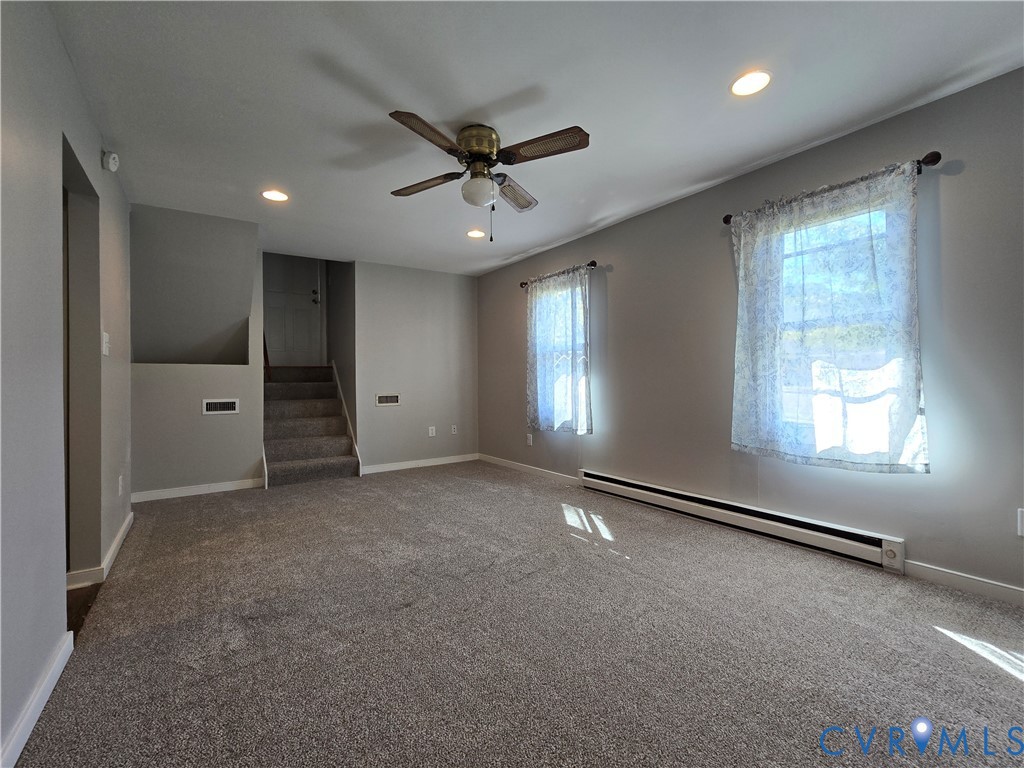 Room with neutral-toned carpeting, recessed ceiling lighting, dual windows, and a ceiling fan with integrated light fixture