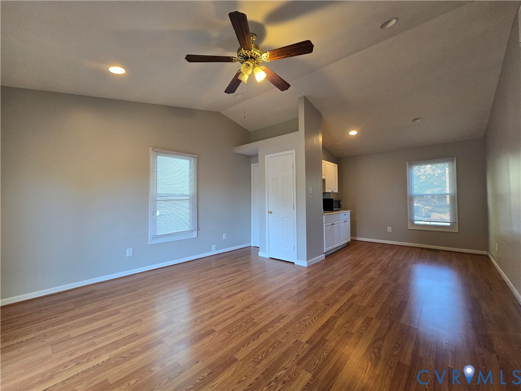 Vaulted ceilings with a multi-blade ceiling fan, wood-finish flooring, recessed lighting, and white interior doors