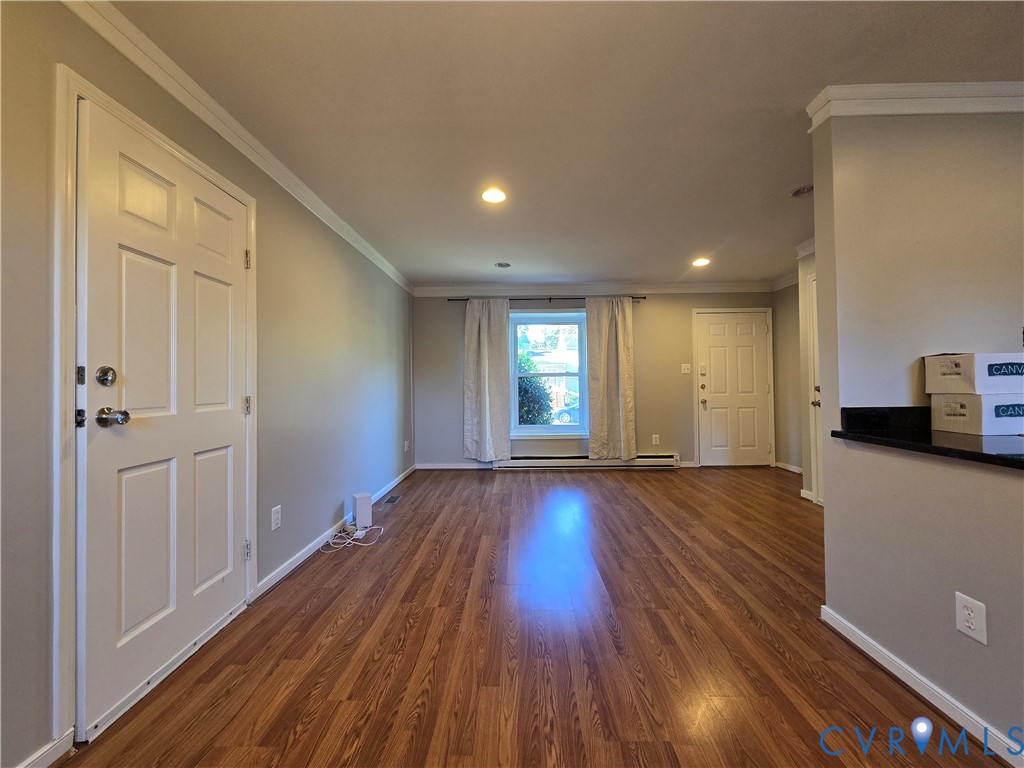 Interior space featuring wood-finish flooring, recessed lighting, crown molding, and a solid-core six-panel door