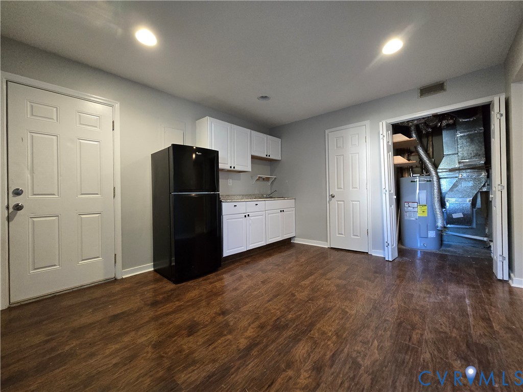 Wood-finish flooring, white shaker-style cabinetry, solid-surface countertops, recessed lighting, and six-panel interior doors
