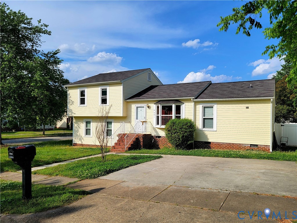 Split-level exterior featuring horizontal siding, a brick foundation, a front bay window, and a concrete driveway