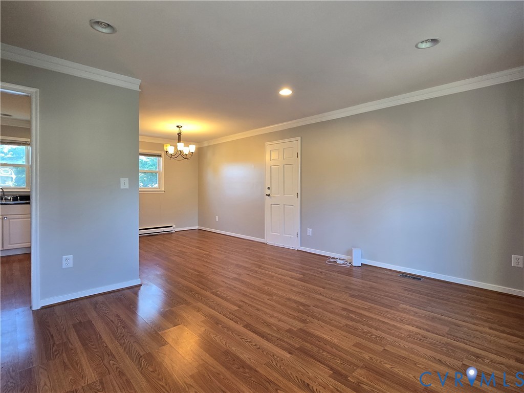 Wood-finish flooring, recessed ceiling lighting, crown molding, and six-panel interior door