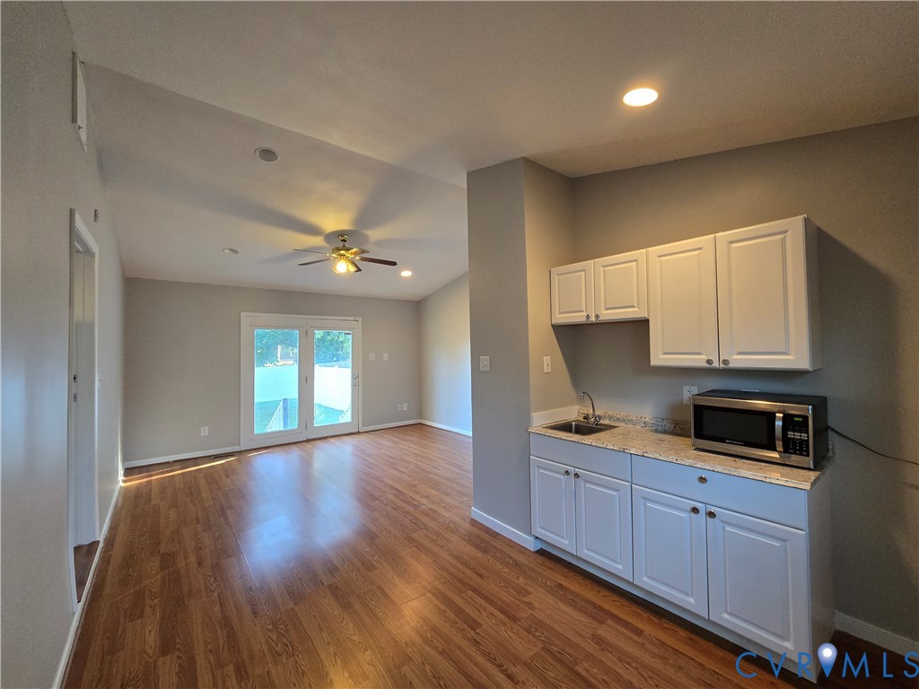 Wood-finish flooring, white shaker-style cabinetry, stone-finish countertops, recessed lighting, and French doors