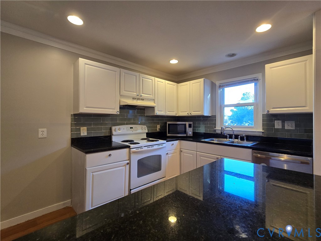 Kitchen featuring white cabinetry, dark stone countertops, grey subway tile backsplash, stainless steel sink with a gooseneck faucet, and recessed lighting