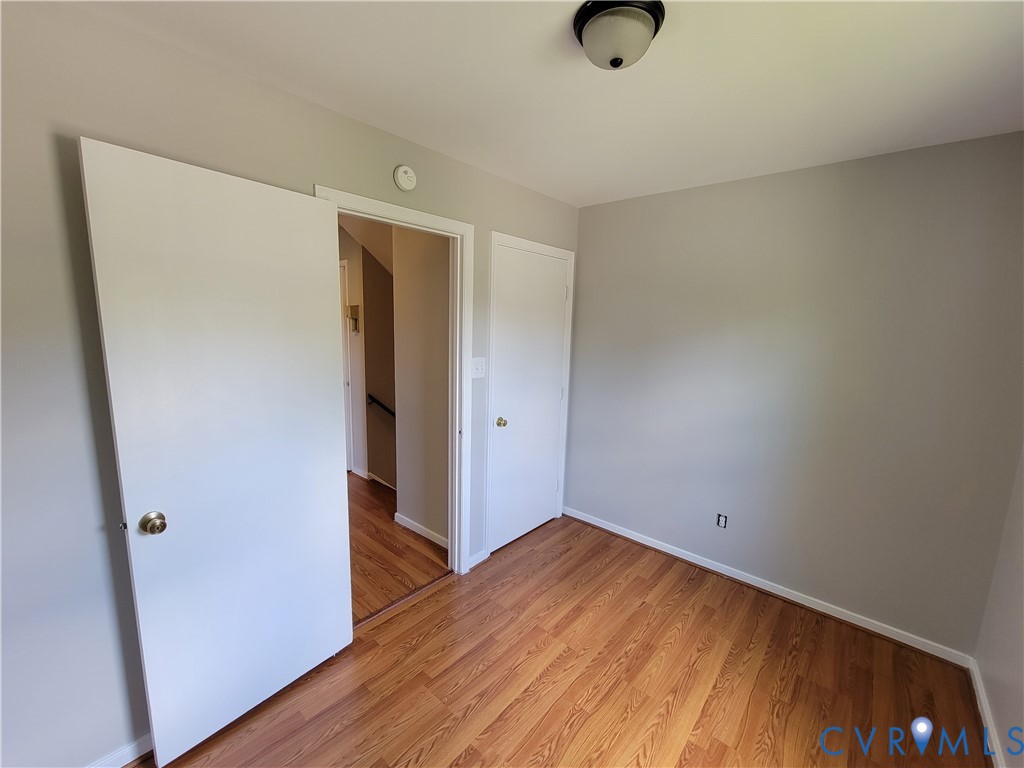 Room featuring wood-finish flooring, neutral wall paint, and a ceiling-mounted light fixture