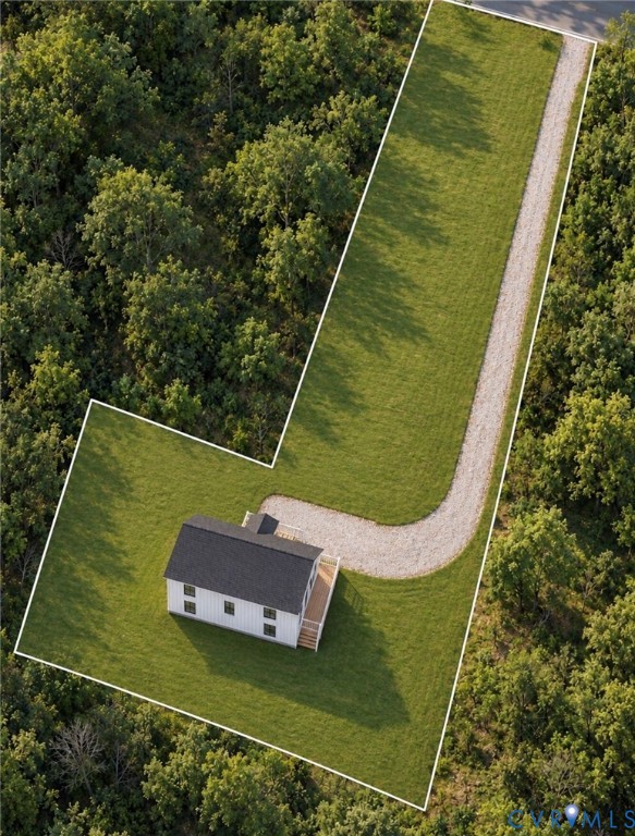 Aerial perspective of property featuring a rectangular structure, a gravel driveway, and surrounding forested area