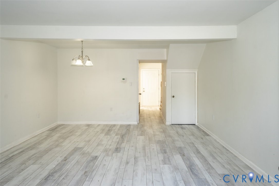 Interior space featuring wood-finish flooring, neutral wall tones, and a multi-light overhead pendant fixture Interior space featuring wood-finish flooring, neutral wall tones, and a multi-light overhead pendant fixture