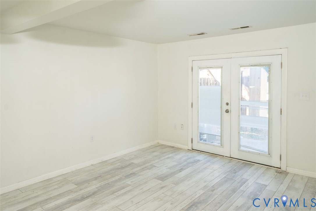 Interior space featuring wood-finish flooring and double glass-paned doors with white trim Interior space featuring wood-finish flooring and double glass-paned doors with white trim