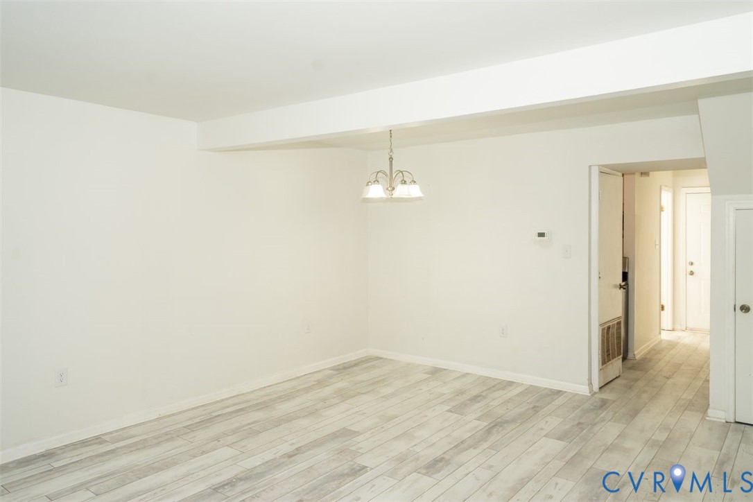 Neutral-toned wood-finish flooring, white walls, and a multi-light brushed nickel pendant fixture Neutral-toned wood-finish flooring, white walls, and a multi-light brushed nickel pendant fixture