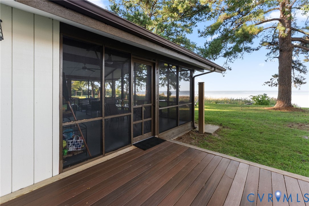 Screened-in porch with metal framing, wooden deck, vertical siding, and waterfront scenery