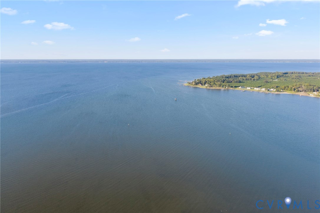 Aerial perspective of waterfront parcel featuring extensive shoreline, direct water access, and surrounding mature timber