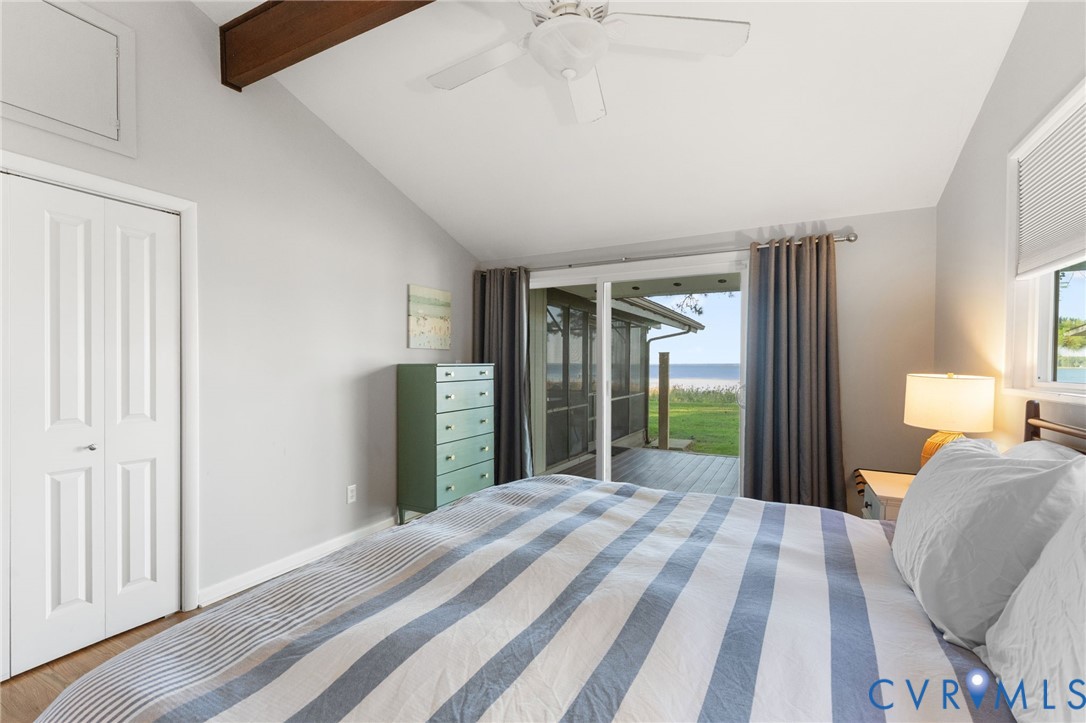 Vaulted ceiling with exposed wood-finish beam, ceiling fan, and sliding glass door with access to a covered outdoor space